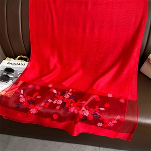 Detail of red silk scarf showing intricate floral embroidery and organza patchwork texture