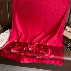 Close-up of red silk scarf featuring floral embroidery and jacquard satin texture