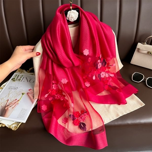 Silk-like crimson scarf with floral embroidery and sheer mesh trim displayed on a hanger