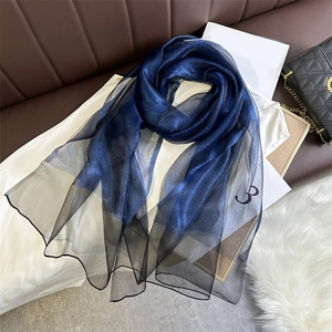 Detail of gradient blue to black silk scarf featuring metallic shimmering fabric texture