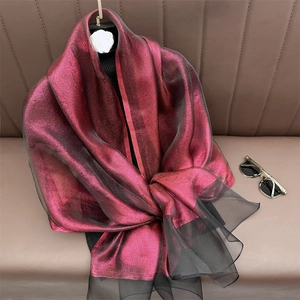 Burgundy silk-like scarf with black sheer trim and metallic luster on leather background