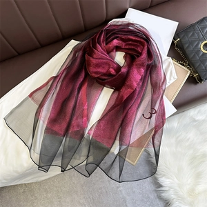 Detail of burgundy shimmering pashmina scarf with black sheer trim and layered texture