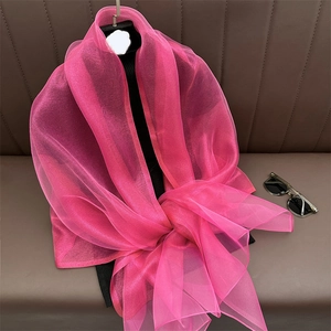 Detail of lightweight bright pink translucent silk scarf draped on a dark textured surface