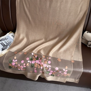 Macro detail of silk wool scarf with intricate floral embroidery on champagne fabric