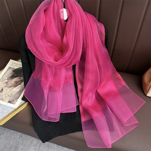 Close-up of bright pink silk scarf with shimmering metallic threads and soft texture