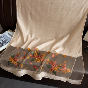 Detail of floral embroidery and pearl accents on a champagne silk-wool scarf shawl