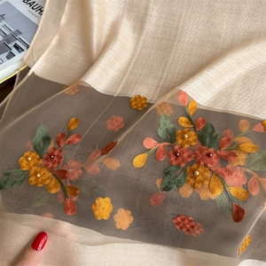 Detail of silk scarf featuring colorful flower embroidery and delicate pearl embellishments