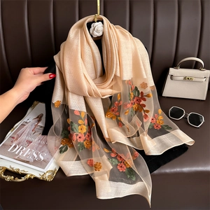 Detail of floral embroidery and sheer mesh on elegant champagne silk scarf shawl