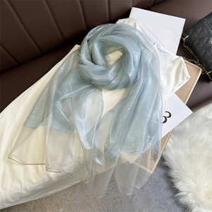 Detail of light blue glitter scarf with sheer metallic finish on white top and bag