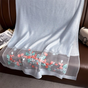 Detail of silk scarf showing light blue embroidery flowers and pearl beads on organza