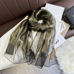 Detail of sheer black scarf with shimmering gold glitter on elegant textured fabric
