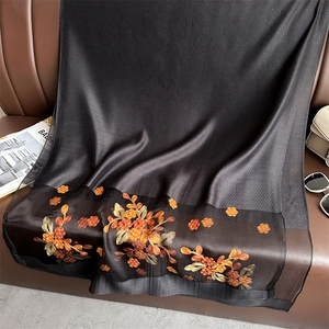 Detail of silk scarf with orange floral embroidery on black satin fabric with accessories