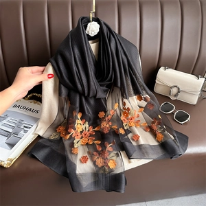 Detail of floral embroidery and pearl accents on elegant black silk blend shawl