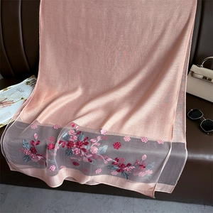 Detail of pink silk scarf with floral embroidery and geometric weave on premium fabric