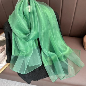 Detail of elegant green translucent silk scarf fabric texture on a black sweater