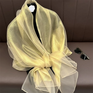 Detailed macro view of the shimmering gold organza texture and sheer metallic fabric