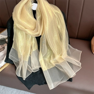 Detail of gold shimmering scarf featuring sheer tulle patchwork hem on black clothing