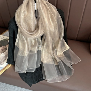 Close-up of champagne gold scarf featuring metallic shimmer and sheer organza paneling