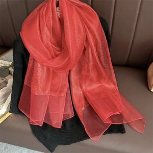 Detail of red sheer pashmina scarf with subtle shimmer on dark leather background