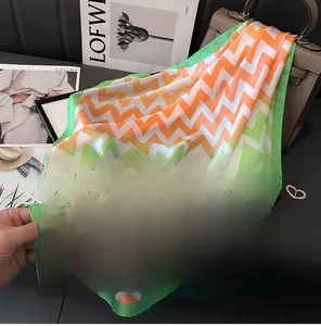 Détail du foulard en soie de 70cm avec motifs vagues orange et vert et bords fins