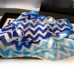 Détail d'un foulard léger en soie synthétique avec motif de vagues bleues et blanches