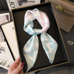 Élégant foulard en soie à dégradé bleu et rose présenté sur un plateau avec des accessoires