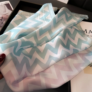 Détail du motif à vagues dégradé bleu et rose sur un foulard carré en soie pour femme