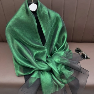 Close-up of emerald silk scarf with shimmer finish and black mesh detail trim