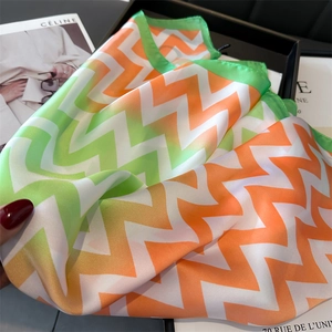 Gros plan d'un foulard en soie avec zigzag dégradé orange et vert et coutures de bord fines