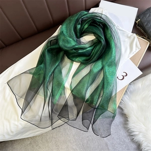 Detail of dark green shimmering scarf showing fine mesh texture and glitter finish