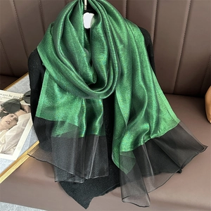 Detail of emerald green metallic fabric joined with black organza on a long scarf