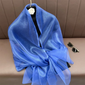 Detail of royal blue sheer scarf texture and glossy silk fabric draped on leather