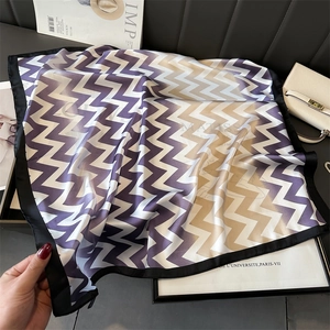 Détail d'un foulard en soie à motifs ondulés violet et champagne avec bordure noire