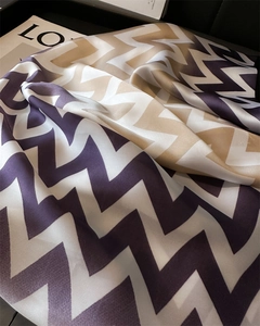 Détail de foulard en satin à motif de vagues géométriques violet et or avec texture