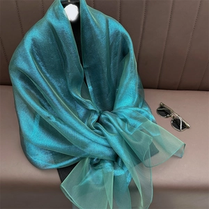 Close-up of metallic silk scarf fabric in elegant peacock green with textured folds
