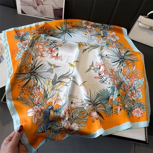 Detail of silk scarf with tropical parrot and floral print on premium black leather