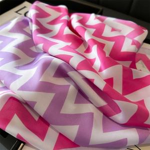 Gros plan d'un foulard en soie à chevrons roses et violets avec une texture satinée