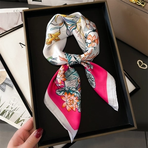 Detail shot of a silk square scarf with hummingbird and floral print in pink and white