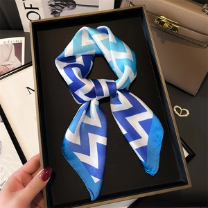 Détail d'un foulard en soie noué en boucle avec motif zigzag bleu et texture lisse