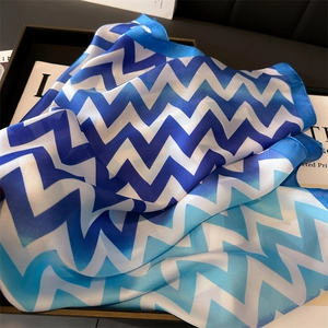 Détail d'un foulard en soie au motif de vagues dégradées bleues et texture satinée