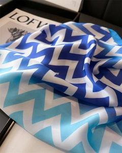 Détail d'un foulard en soie avec motifs de vagues dégradées bleues sur plateau