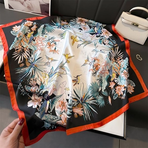 Detailed view of the square silk scarf with bird and flower print and orange border