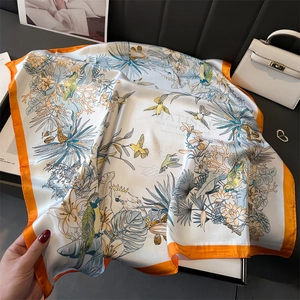 Detailed close-up of a 70cm silk scarf with vibrant tropical bird and floral patterns