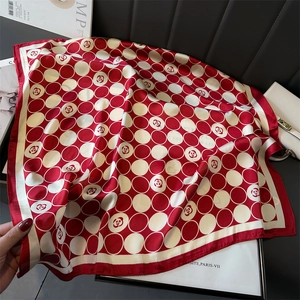 Détail de foulard en soie à pois rouges et blancs avec motif camélia sur un magazine