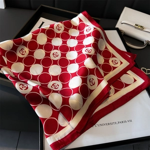 Détail d'un foulard en soie à pois camélia rouge drapé sur un sac ivoire chic