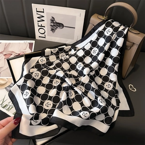 Carré de soie 70cm noir et blanc avec pois camélia drapé sur un sac à main en cuir souple