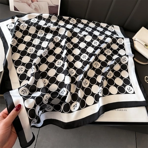 Détail d'un foulard carré en soie avec motifs camélia classiques et pois élégants