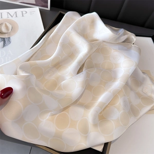 Gros plan d'un foulard en soie champagne avec pois blancs et motifs de roses délicats