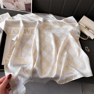 Détail d'un foulard en soie imprimé artistique drapé sur un sac à main en cuir chic