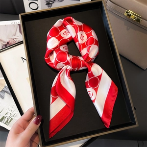 Gros plan d'un foulard en soie à fleurs rouge et blanc noué dans un coffret cadeau